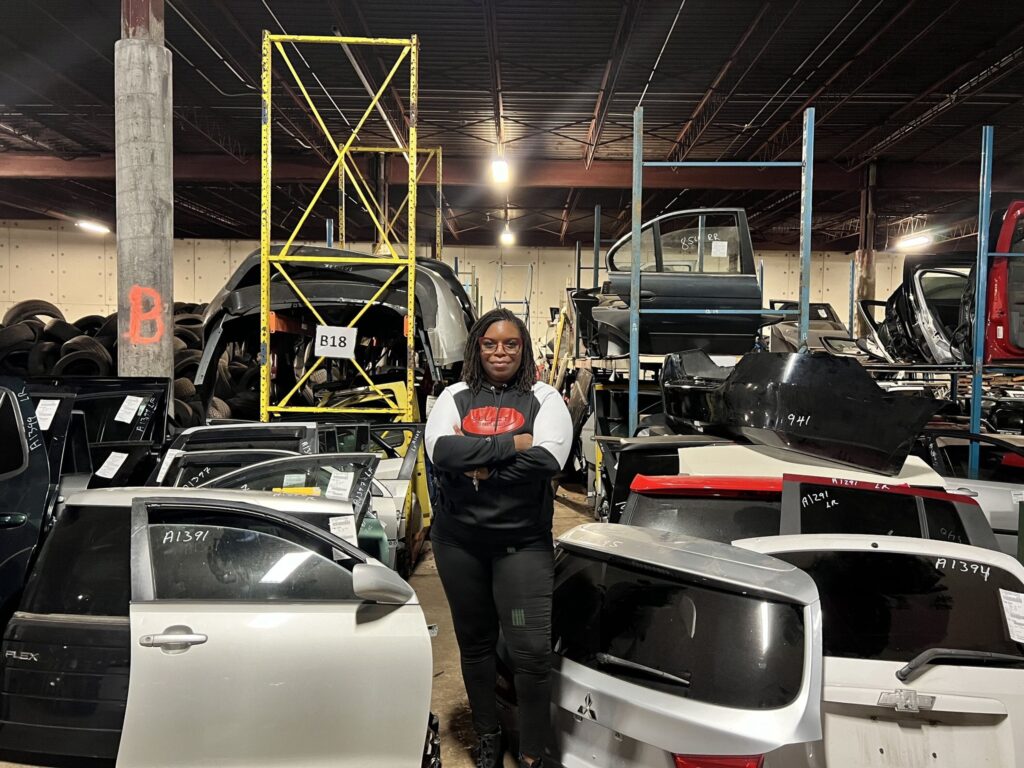 Select Auto Parts owner in indoor auto recycling warehouse with vehicle parts.